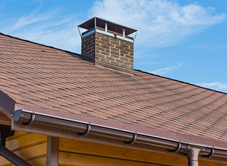 rectangle brown brick chimney on the shingle roof